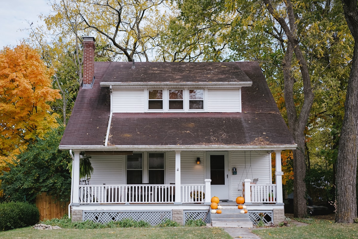 A modest white craftsman home with a covered front porch on an autumn day — an owner's most valuable asset